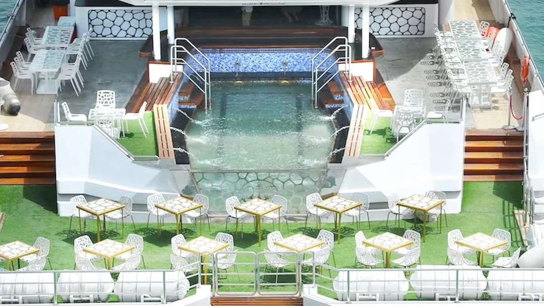 Lotus Mega Yacht deck with dining tables and pool, Dubai Marina cruise.