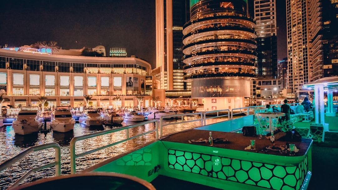 Mega yacht deck with dining setup, Dubai Marina skyline at night.