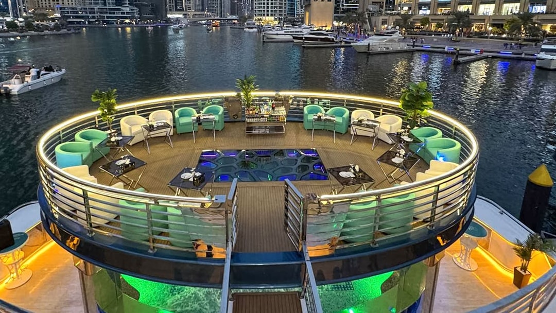 Lotus Mega Yacht deck with seating and tables, Dubai Marina in the background.