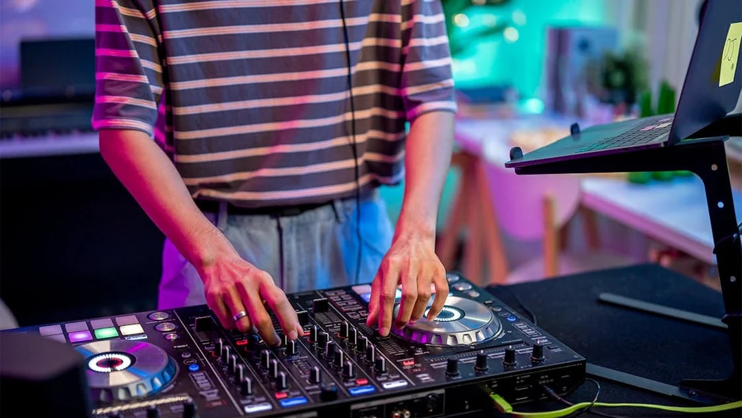 DJ mixing music on a controller in a vibrant studio setting.