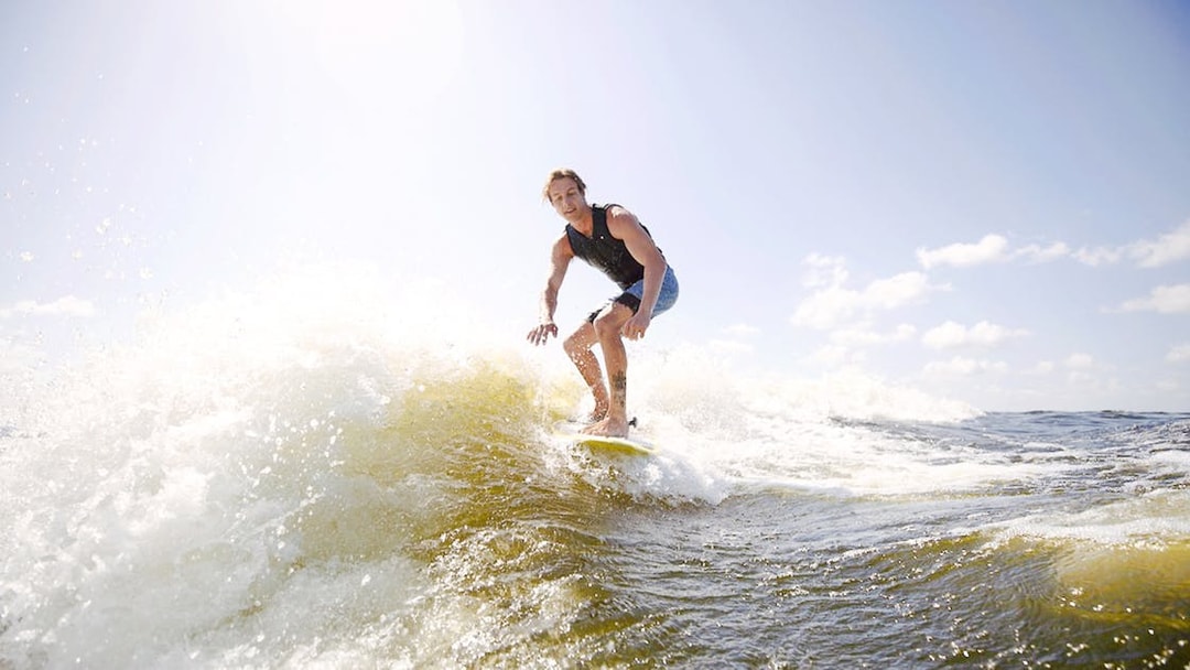 Man wakeboarding on waves in Dubai under a clear sky.