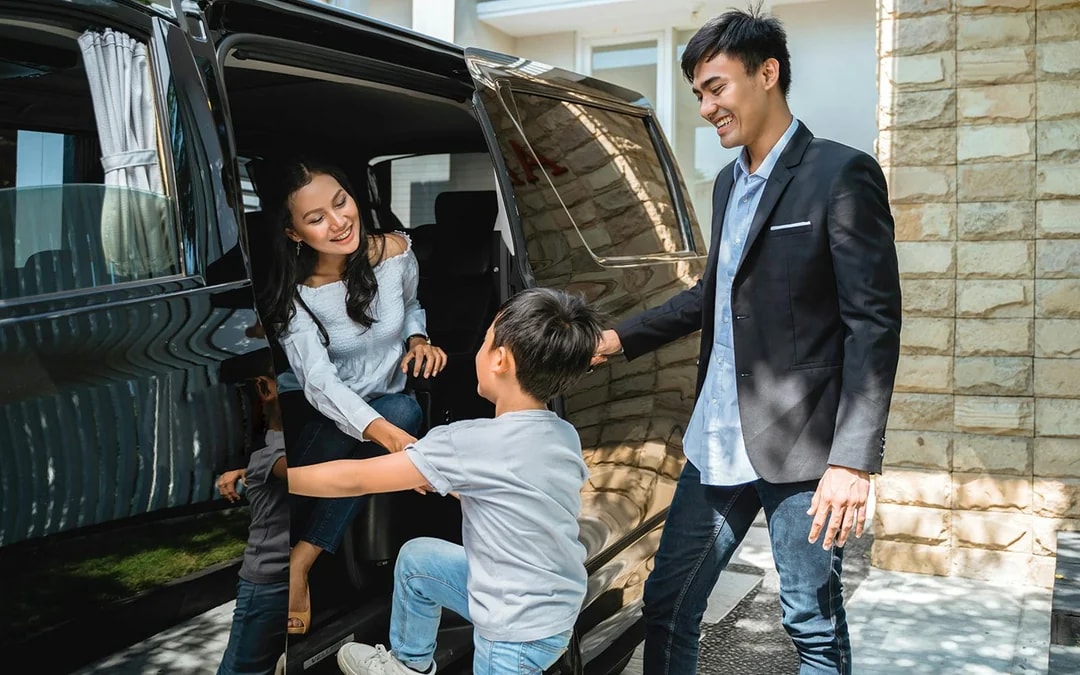 Couple entering vehicle for roundtrip transfer with child assisting.