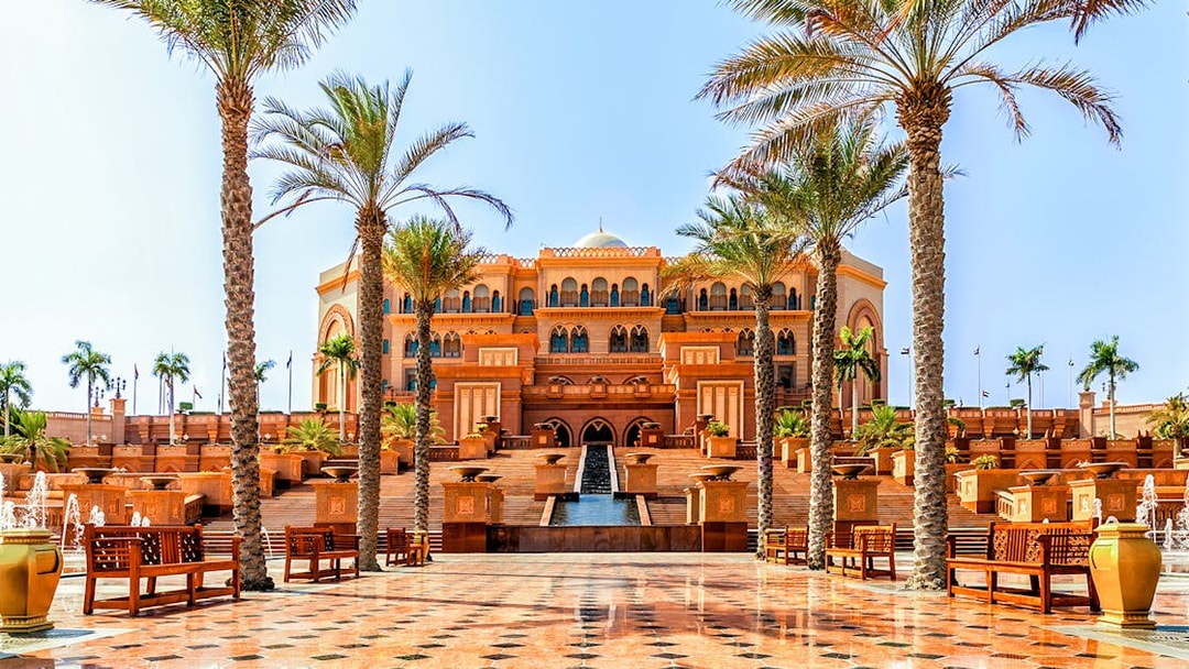 Emirates Palace entrance with palm trees and fountains, Abu Dhabi.
