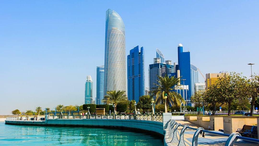 Abu Dhabi Corniche with modern skyscrapers and waterfront promenade.