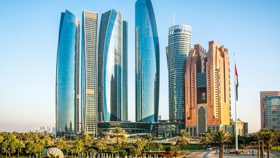 Etihad Towers skyline in Abu Dhabi with surrounding gardens and fountains.