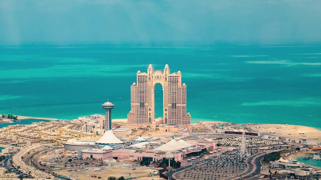 Aerial view of Abu Dhabi skyline with Etihad Towers and turquoise sea.