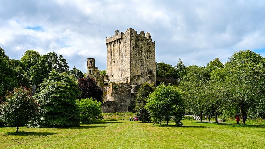 Blarney Castle and Gardens surrounded by lush greenery in Ireland.