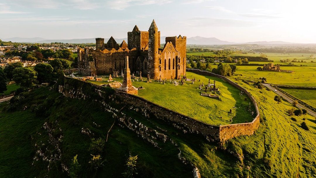 Aerial view of the Rock of Cashel, Ireland, with surrounding green landscape.