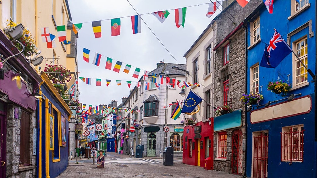 Colorful buildings and international flags on the main high street in Galway City.