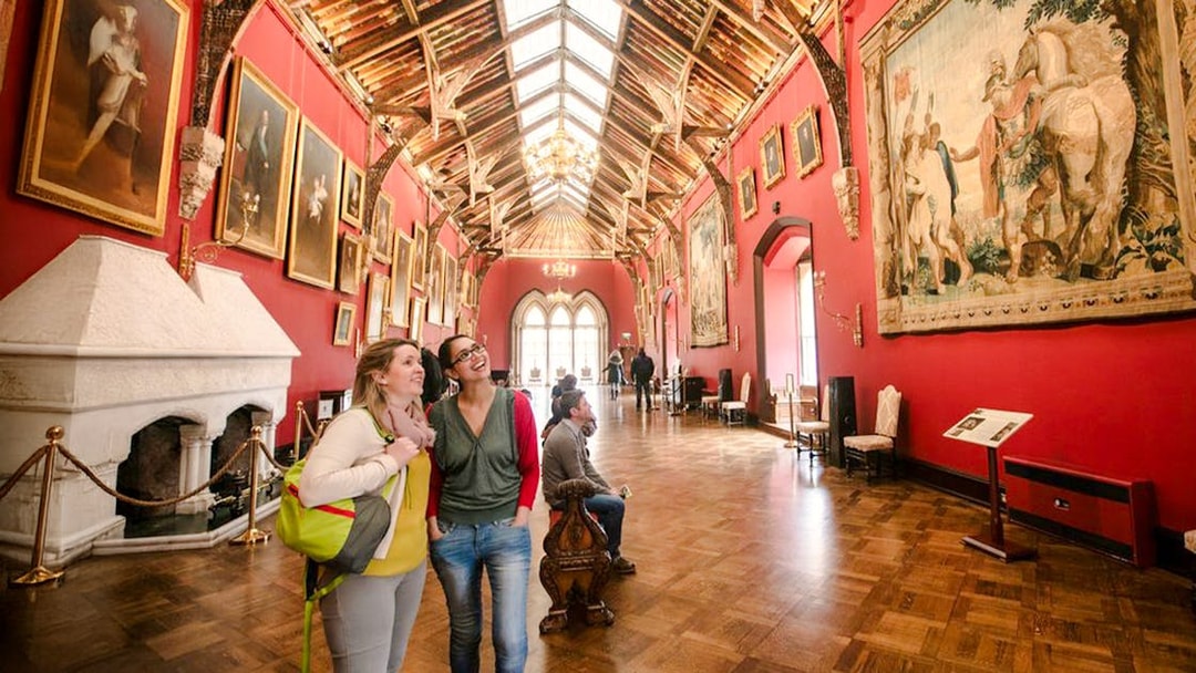 Visitors exploring the art-filled gallery of Kilkenny Castle with ornate ceiling and historic paintings.
