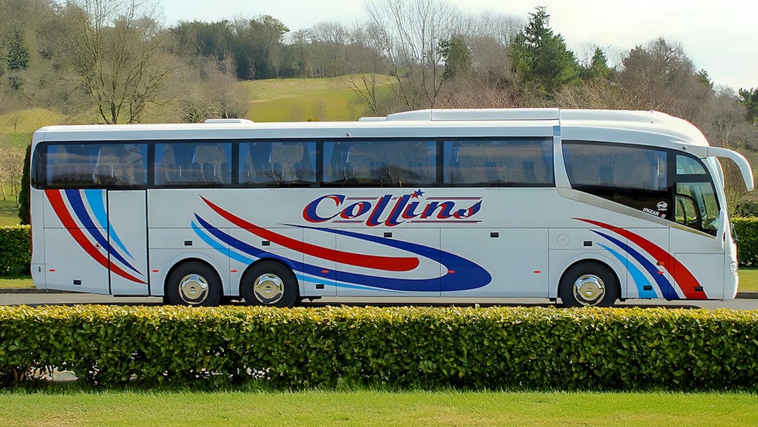 Tour coach parked in a scenic countryside setting.