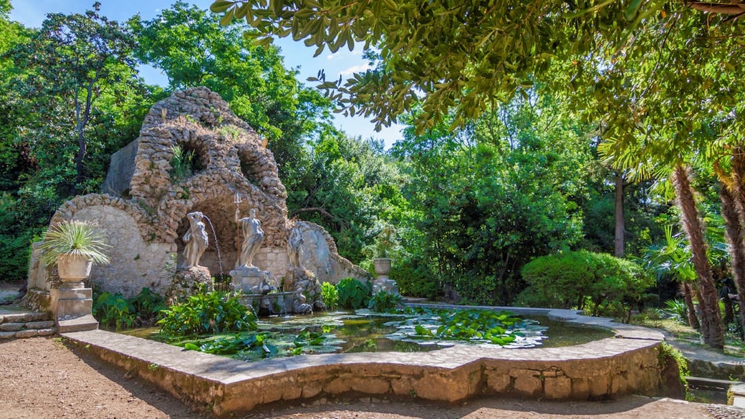 Stone grotto with statues and pond in lush garden, Game of Thrones driving tour location.