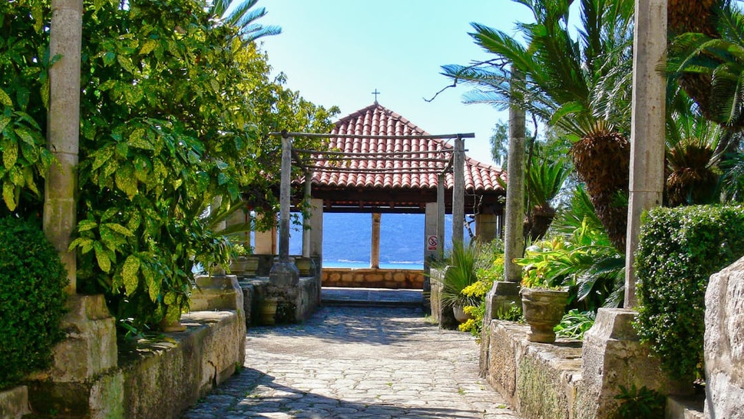 Stone pathway leading to a pavilion with a tiled roof, surrounded by lush greenery, on the Game of Thrones Driving Tour.