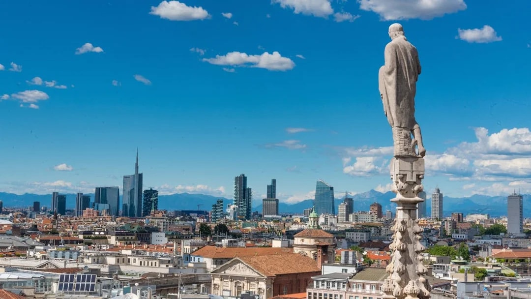 Rooftop view of Milan cityscape from Duomo with skyline and mountains.