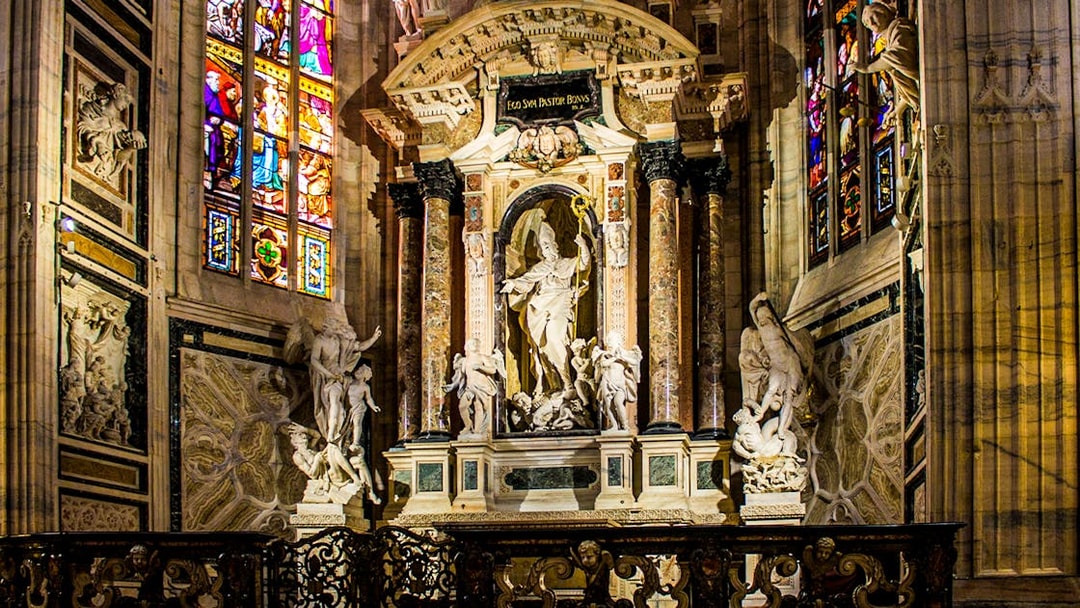 Interior of Milan Cathedral featuring ornate sculptures and stained glass windows, Italy.