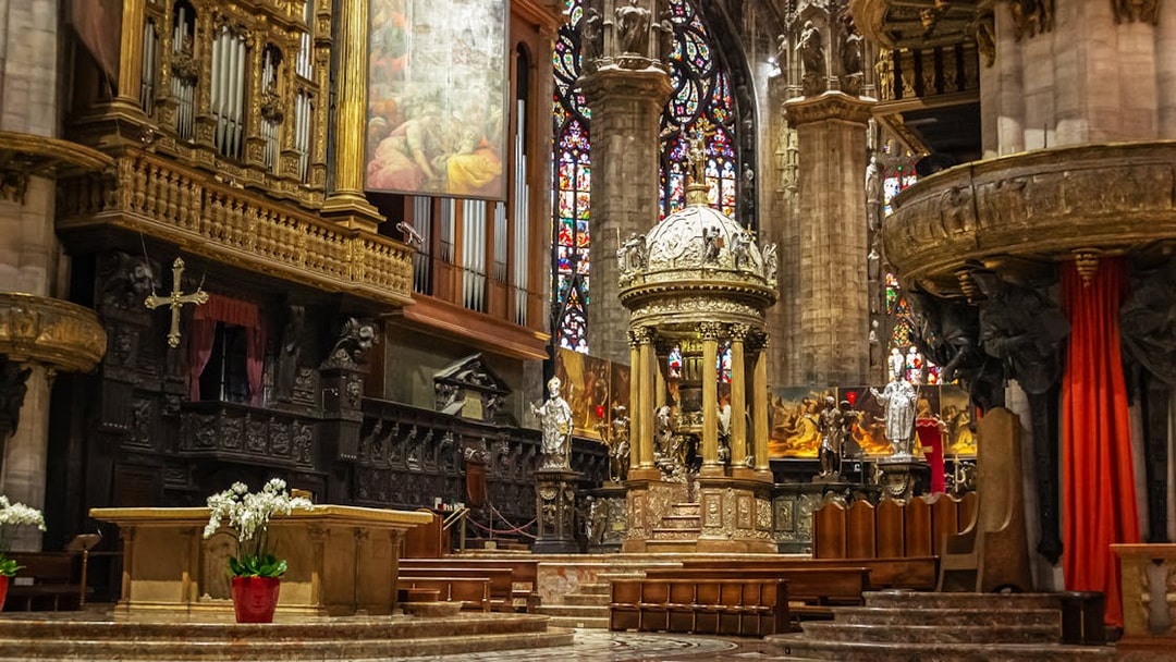 Presbytery and altar inside Duomo di Milano with ornate carvings and stained glass windows.