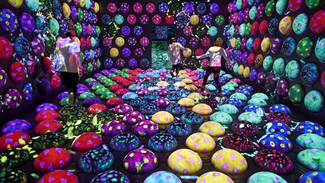 Visitors exploring colorful interactive exhibit at E・ZO FUKUOKA teamLab Forest.