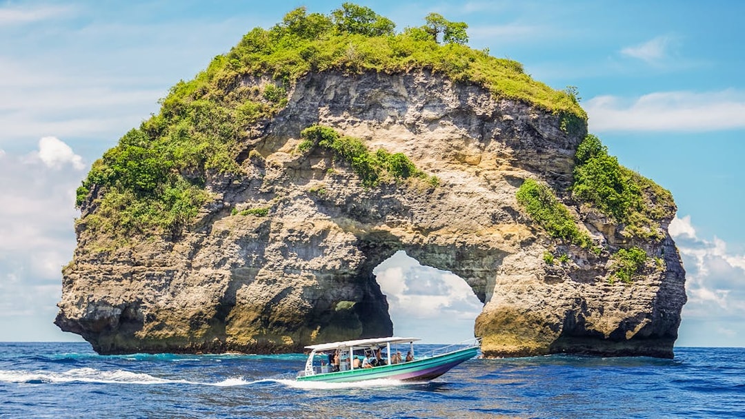 Speedboat with tourists approaching Nusa Penida Island, Bali, showcasing unique coastal views.