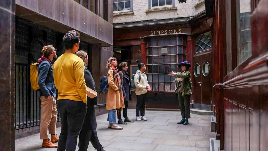 Tour group listening to a guide outside Simpsons in London on the Heart of 'The City' Food Tour.