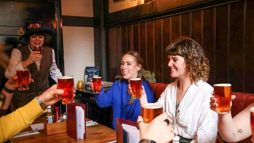 Group enjoying pints at a London pub on the Heart of 'The City' Food Tour.