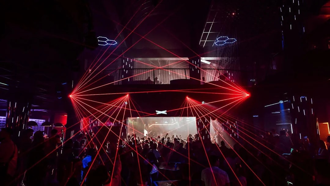 Nightclub with red laser lights and crowd at Eden on Saturdays event.