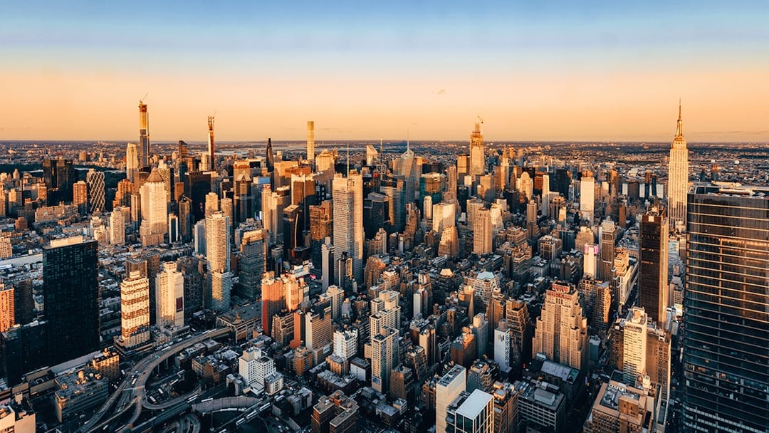 Aerial view of New York City skyline at sunset, featuring skyscrapers and urban landscape.