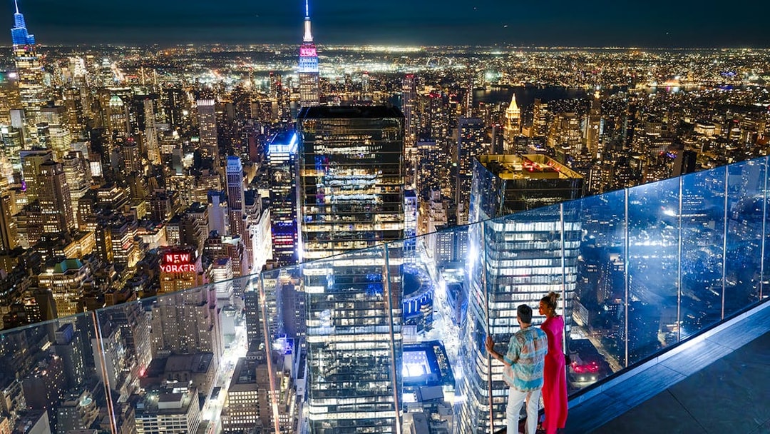Couple enjoying New York City skyline from Edge observation deck at night.