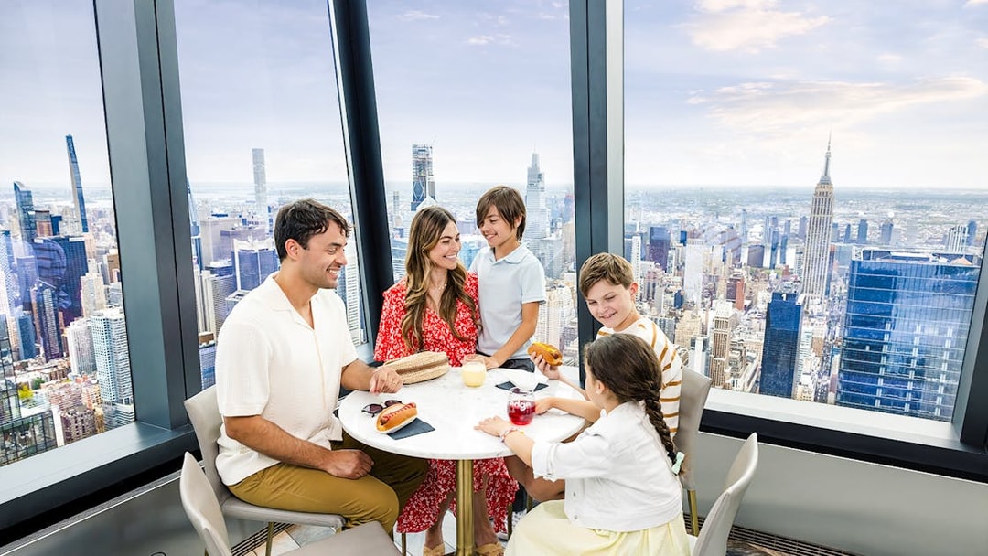 Family dining at Edge's indoor sky deck with New York City skyline views.