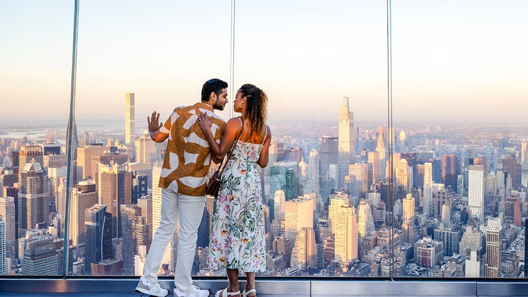 Couple enjoying sunset view from The Edge, New York City skyline in background.