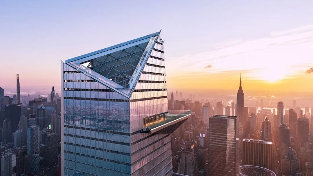 Visitors on Edge Observation Deck with New York City skyline at sunset.