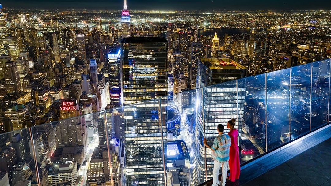 Couple enjoying night view of New York City skyline from Edge Observation Deck.