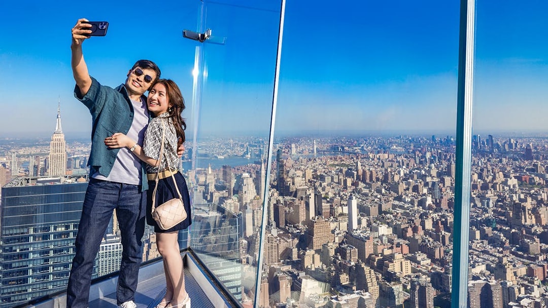 Couple taking a selfie at Edge Observation Deck with New York City skyline.