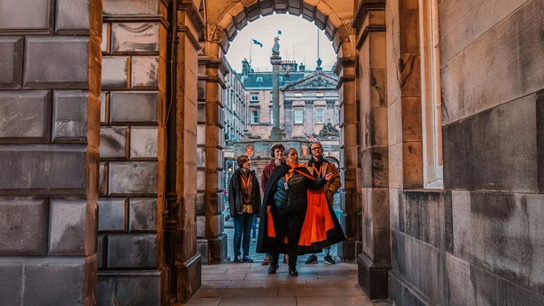 Group on guided tour under archway in Edinburgh Old Town.