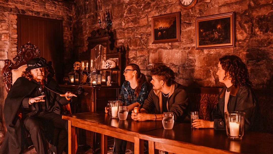 Edinburgh ghost tour guide narrating stories to visitors in a dimly lit underground room.