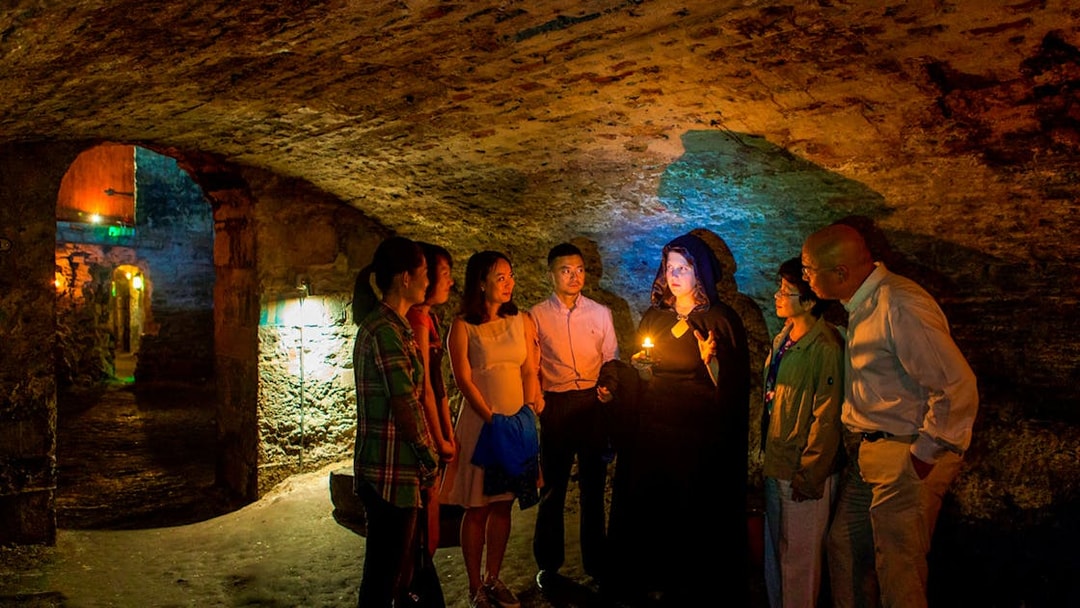 Group on Edinburgh ghost tour in underground vaults with guide holding candle.