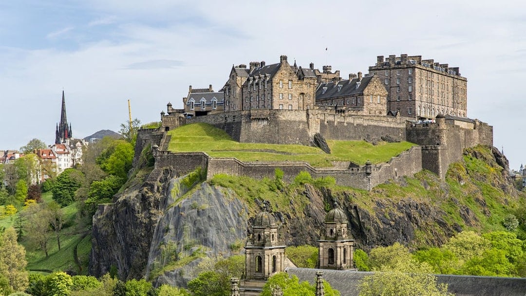Edinburgh Castle on Castle Rock, surrounded by lush greenery, Scotland.