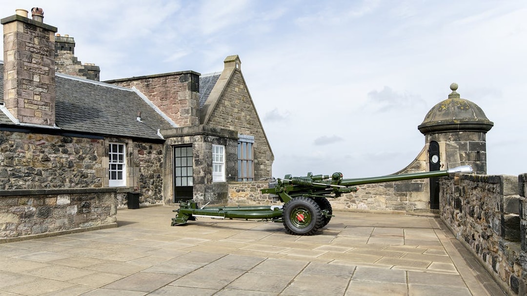 Canon gun on Edinburgh Castle terrace with stone buildings in the background.
