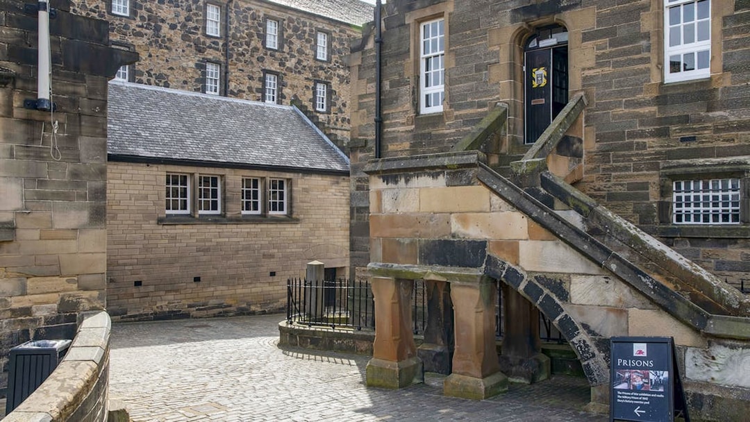 Edinburgh Castle courtyard with historic stone buildings and prison sign.