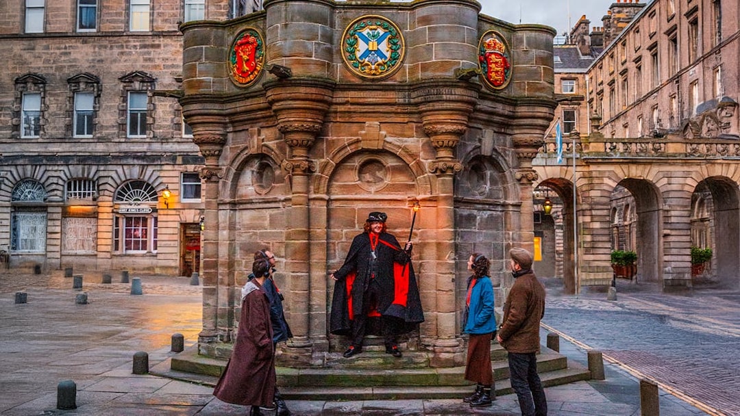 Guide with guests on Ghostly Underground tour in Edinburgh near historic monument.