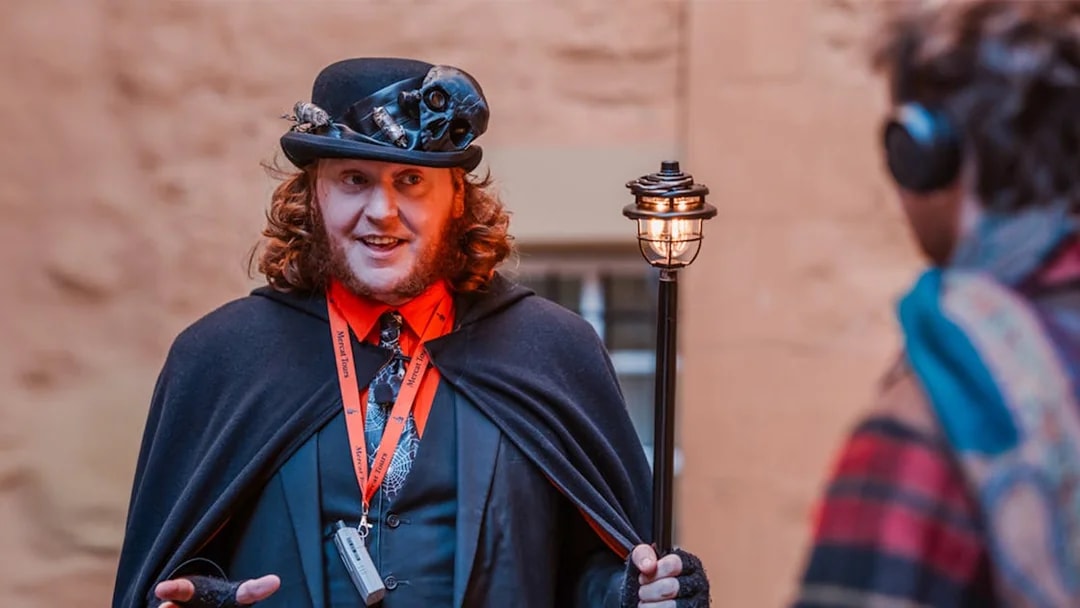 Tour guide in costume leading Edinburgh's Royal Mile ghost tour.