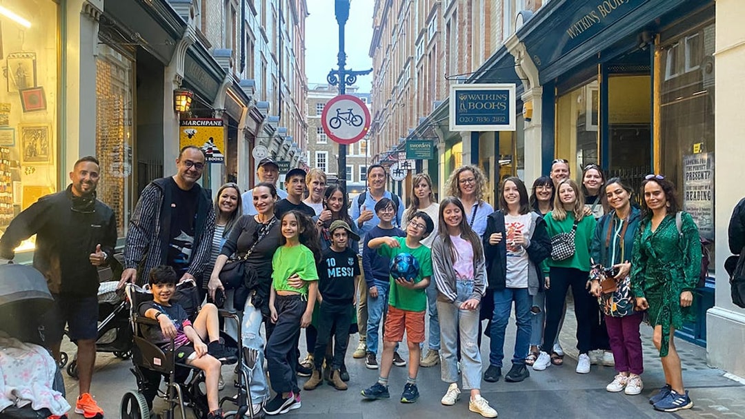 Group of people gathered in a narrow street with shops in the background.