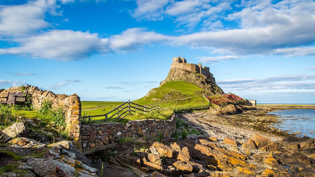 Lindisfarne Castle on rocky hill with stone wall, Northumberland coast, England.