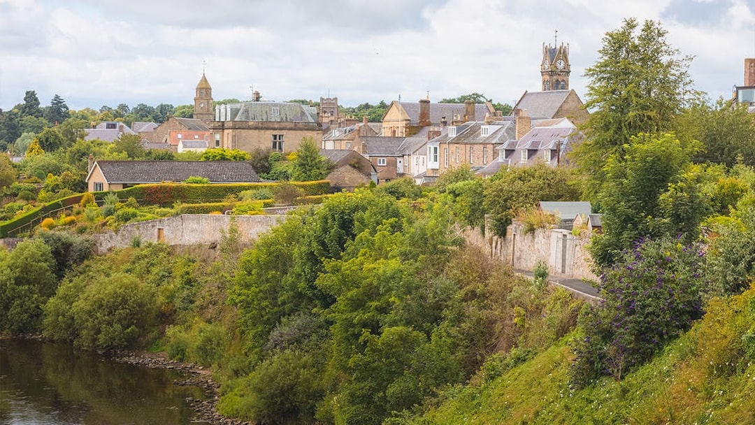 Village Coldstream along River Tweed, Scotland with historic buildings and lush greenery.