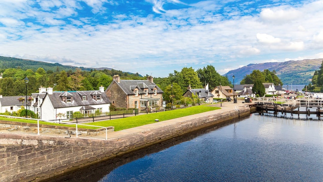 Fort Augustus, Scotland, with canal, historic buildings, and lush greenery.