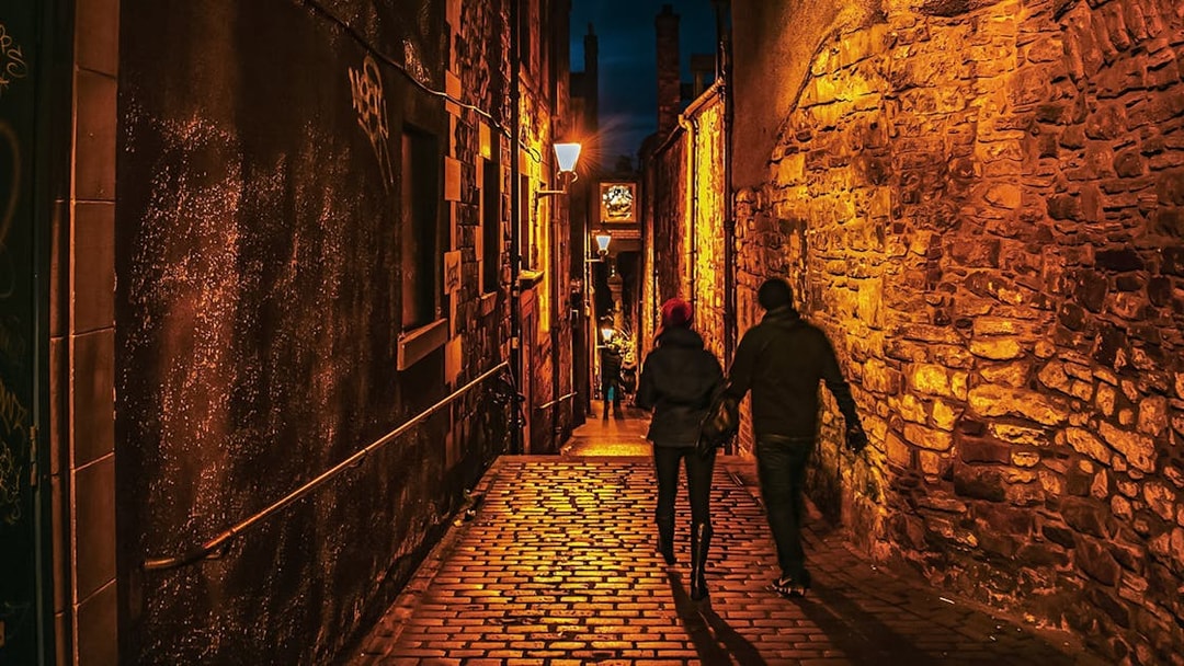 Couple walking through dimly lit cobblestone alley on Extreme Paranormal Activity Tour.
