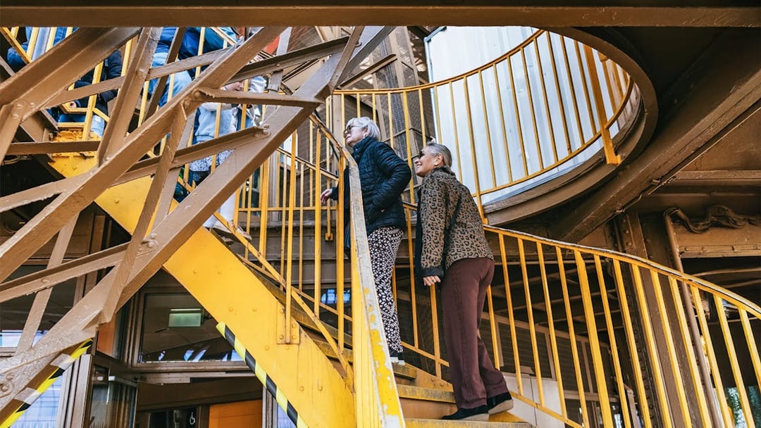 Visitors ascending Eiffel Tower stairs during guided tour in Paris.