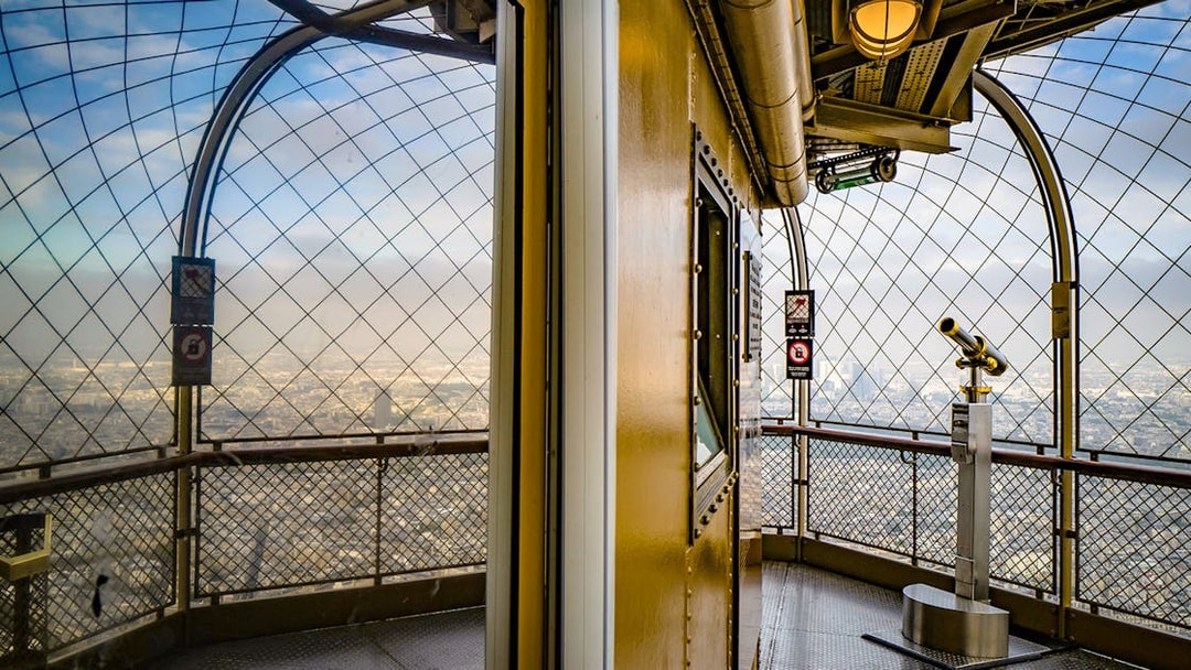 Eiffel Tower observation deck with telescope overlooking Paris.