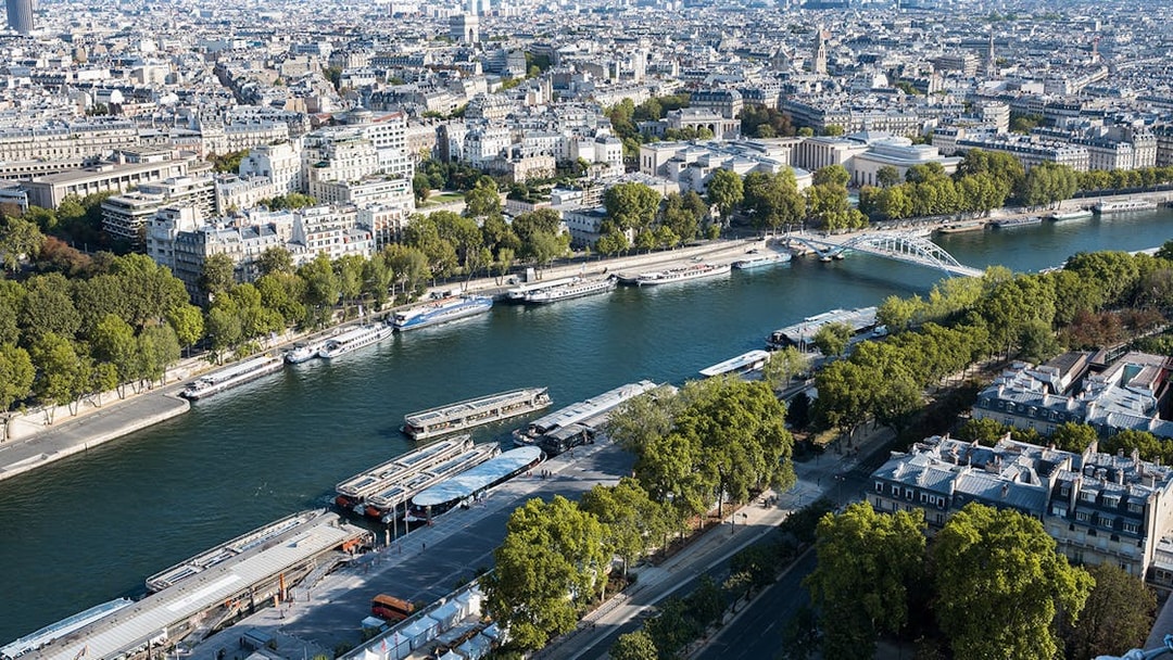 Aerial view of Seine River with cruise boats and Paris cityscape.