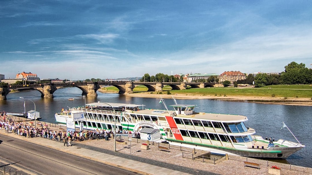 Elbe river cruise ship docked in Dresden with Augustus Bridge in the background.