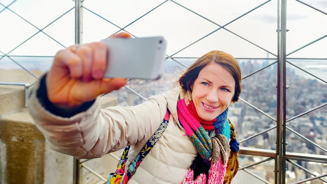 Visitor taking a selfie on the 86th floor of the Empire State Building, New York City.